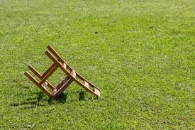 a wooden chair lies upside-down on grass